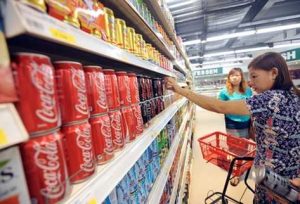 A Myanmar woman takes a can of Coca-Cola from a shelf at a supermarket in Yangon on September 11, 2012.  Coca-Cola has put its stamp of approval on Myanmar's reforms with the first official delivery of the popular soft drink in the country in more than 60 years, the company announced on September 10.   AFP PHOTO/ Soe Than WIN