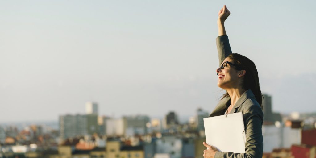 Successful young city business woman raising arm